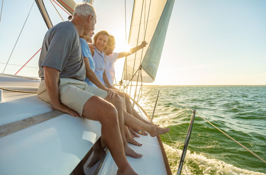 Relaxed group of senior American friends sailing towards horizon on luxury yacht enjoying freedom outdoors in retirement